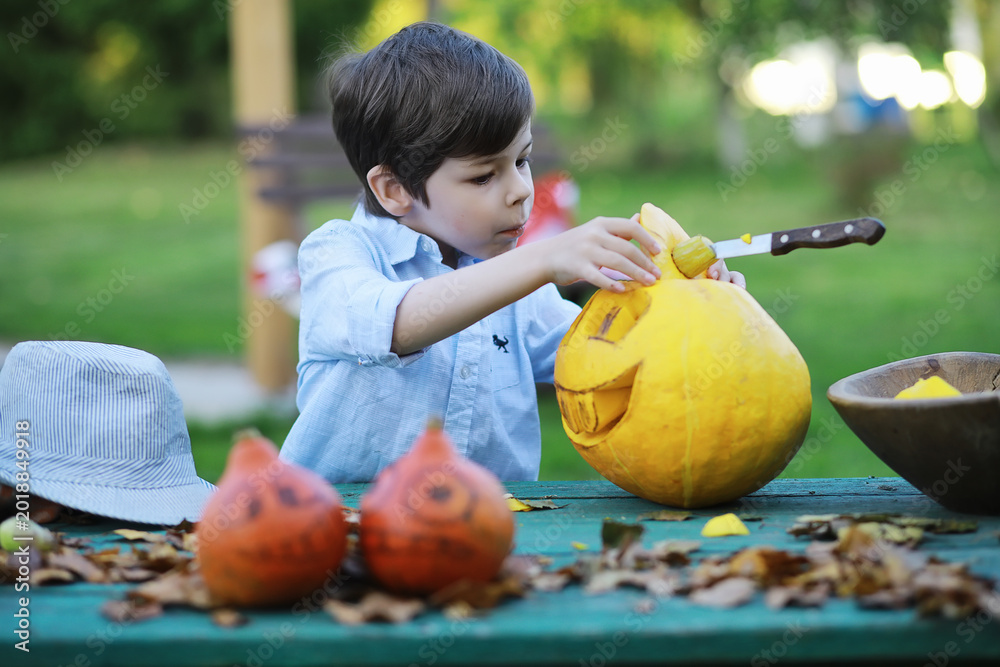 Fototapeta premium Autumn traditions and preparations for the holiday Halloween. A house in nature, a lamp made of pumpkins is cutting out at the table.