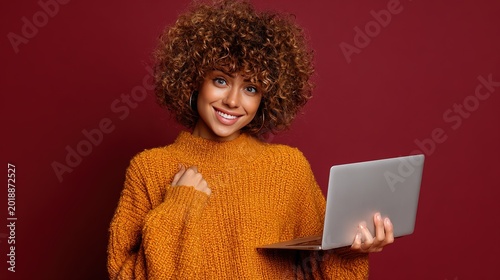 Online Presence: A charming woman with curly hair is comfortably holding a laptop, she looks very friendly and happy.