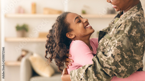 Bild auf Leinwand A soldier hugs a young girl in a home setting