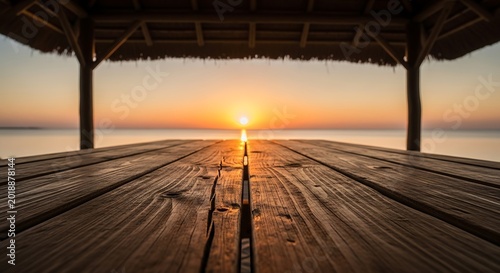 Sunset glow over wooden dock extending into calm ocean waters with thatched roof shelter framing view