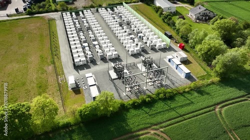 Aerial footage of industrial energy storage facility in industrial area. Battery energy storage system (BESS) instalation. Grid-scale battery storage and substation in  commercial and industrial area.
