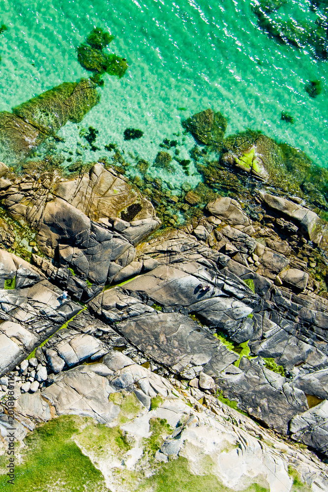 Naklejka premium Rocky shoreline at Dogs Bay near Roundstone, Connemara, County Galway, Ireland. Scenic Atlantic coast with granite boulders and clear water on the Wild Atlantic Way.
