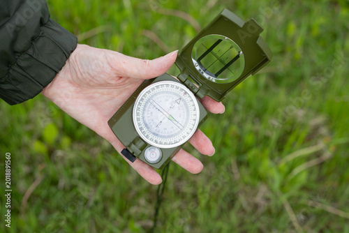 Φωτογραφία Woman's hand displays the dial of a well-worn compass against a background of green grass