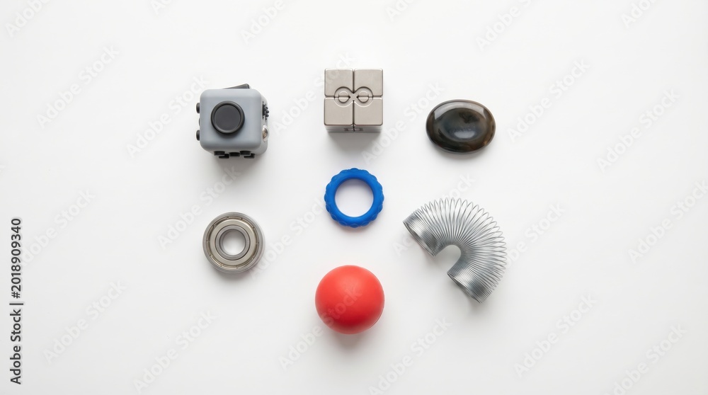 Fototapeta premium Top down view of various sensory fidget toys including cube and slinky on white background as concentration aids for ADHD mind