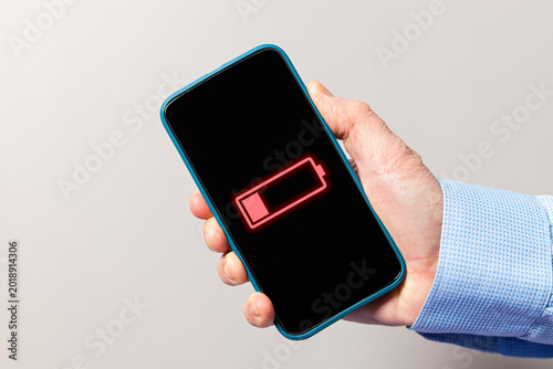 Hand holding smartphone showing low battery icon