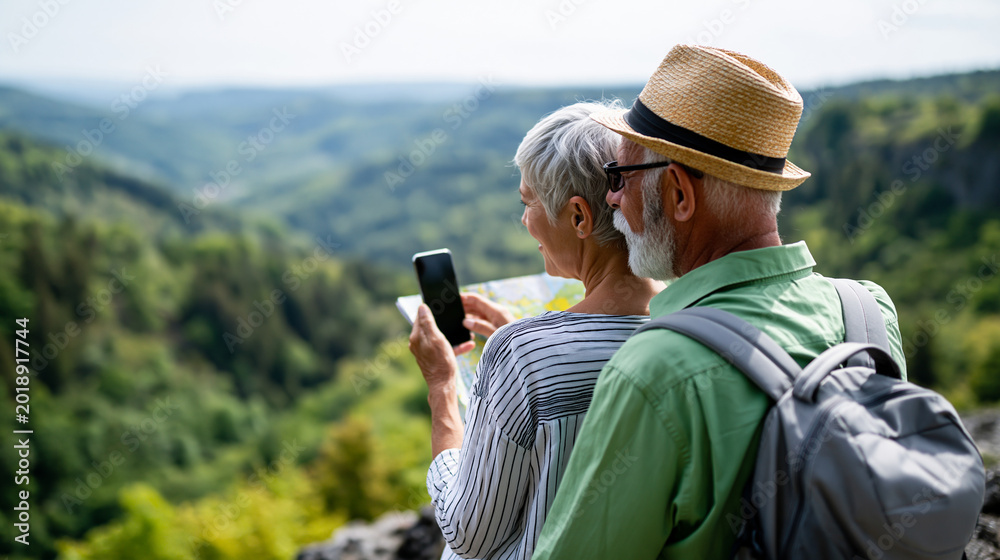 Fototapeta premium Rear view of a senior couple studying a smartphone map during a hike in hilly countryside, mature hiker navigation concept, senior adventure lifestyle photography, hiking with