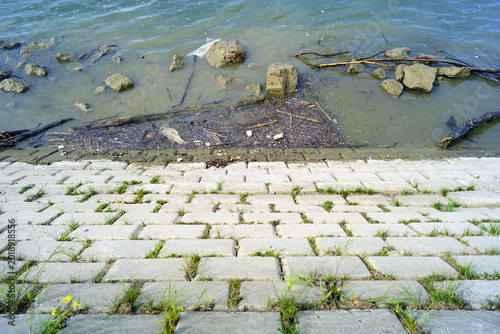 Tableau sur toile Worn embankment meets a band of debris and sediment along the Danube