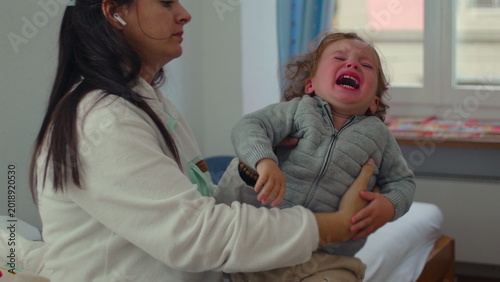 Canvas-taulu Mother comforting distressed toddler in arms, steady embrace patience and emotio
