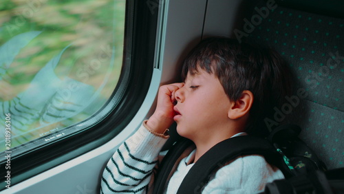 Tableau sur toile Boy sleeping on train with head resting against window creating peaceful travel