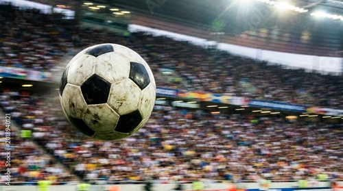 A soccer ball flying through the air in a crowded stadium