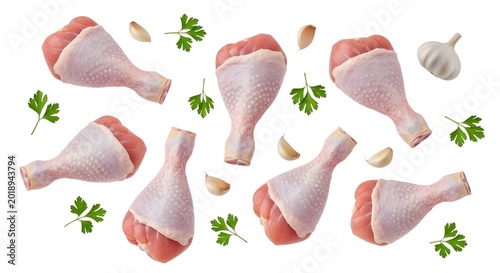 Raw chicken drumsticks with garlic and parsley on white background