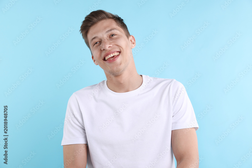 Obraz premium Young man laughing at joke on light blue background