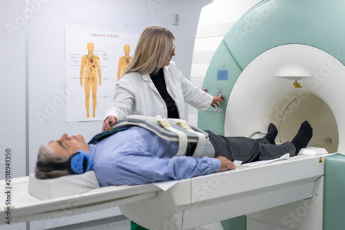 Doctor operating MRI machine for patient lying down, medical imaging procedure in clinic