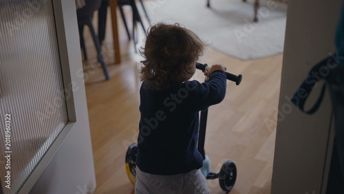 Fotografija Toddler removing helmet then pushing scooter forward before stumbling and pausin