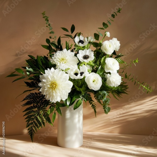 Flowers in a White Vase With Green Leaves Placed on a Light Surface During Br...