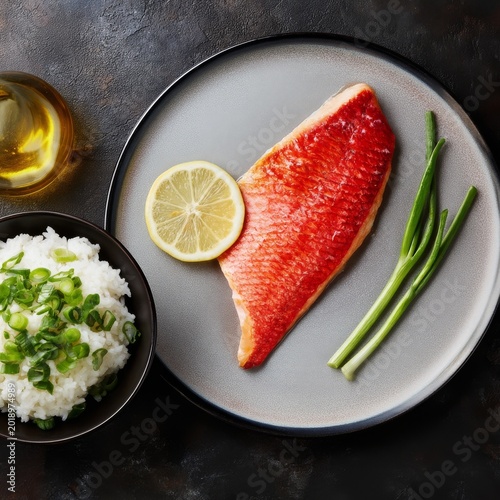 Fresh Salmon With Lemon and Green Onions Served on a Plate Beside Rice in a Bowl