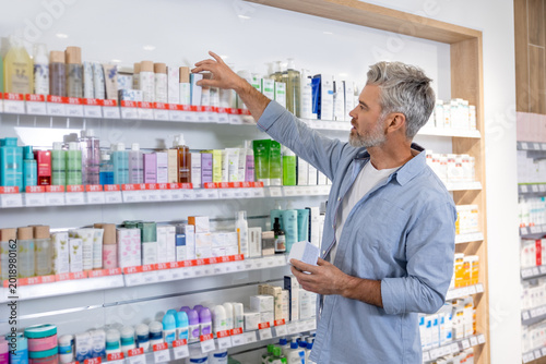 Senior Caucasian man with gray hair holding medical product package