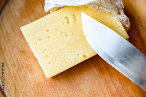 The hand cutting the mold on the spoiled cheese on wooden board.