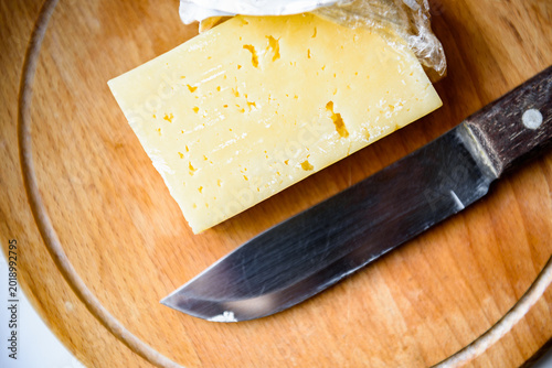Spoiled cheese with mold on wooden cutting board.