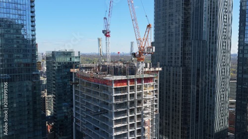 Construction site revealing new skyscraper development with tower cranes lifting materials for urban housing and commercial real estate projects in North America