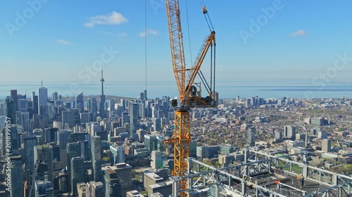 Urban construction crane building skyscraper in Toronto's downtown financial district with office towers, Lake Ontario, and city skyline in background, industry development