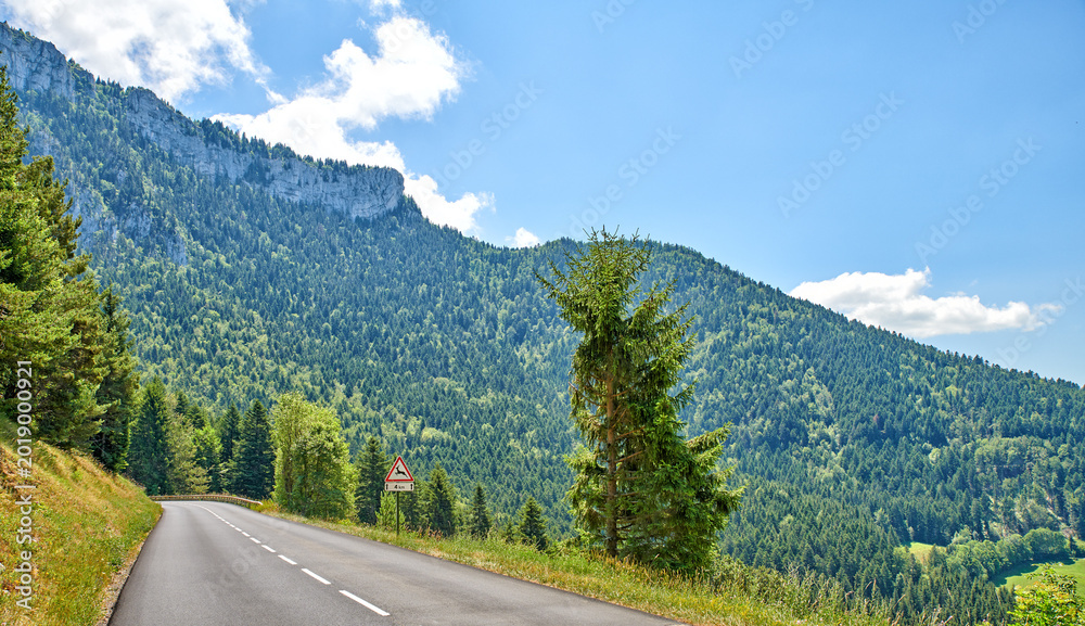 Obraz premium Landscape, mountain and road with sign in nature for travel, tourist destination and journey outdoor. Empty, background and street with scenic route, highway and space for vacation, trip and holiday