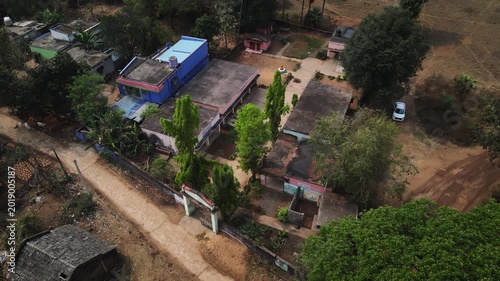 Aerial drone view of a government school located in the rural region of Odisha, India. The scene captures simple school buildings surrounded by greenery and open land.