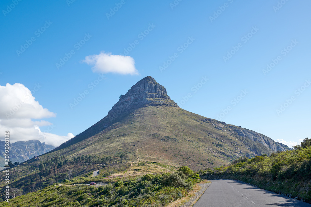 Naklejka premium Blue sky, mountain and road with landscape in nature for travel destination, roadtrip and holiday. Space, hill and street in natural environment for scenic route, getaway journey and highway with car