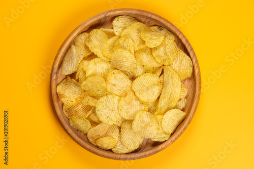 Wavy potato chips filling a wooden bowl