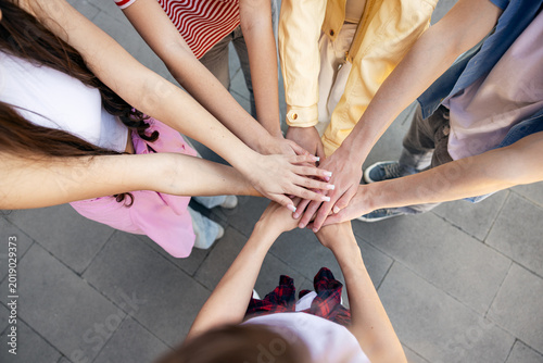 Картината върху платно Group of young people stacking hands showing teamwork