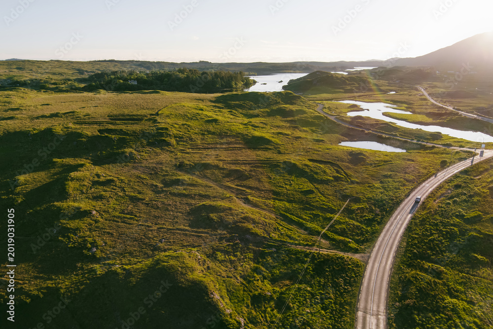 Naklejka premium Roads, lakes and rugged hills spread across the Connemara landscape near Derryclare Lough in County Galway. An aerial view of the wild scenery around Twelve Pines Island in western Ireland.