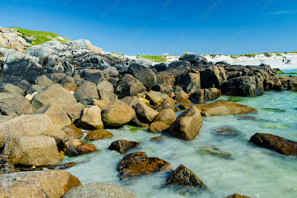 Naklejka premium Rocky shoreline and turquoise water at Dogs Bay near Roundstone, Connemara, County Galway. Scenic white sand beach on the Wild Atlantic Way beside Gurteen Bay, Ireland