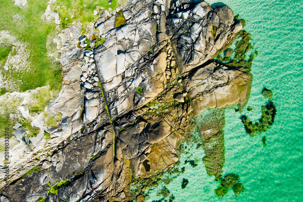 Naklejka premium Rocky shoreline at Dogs Bay near Roundstone, Connemara, County Galway, Ireland. Scenic Atlantic coast with granite boulders and clear water on the Wild Atlantic Way.