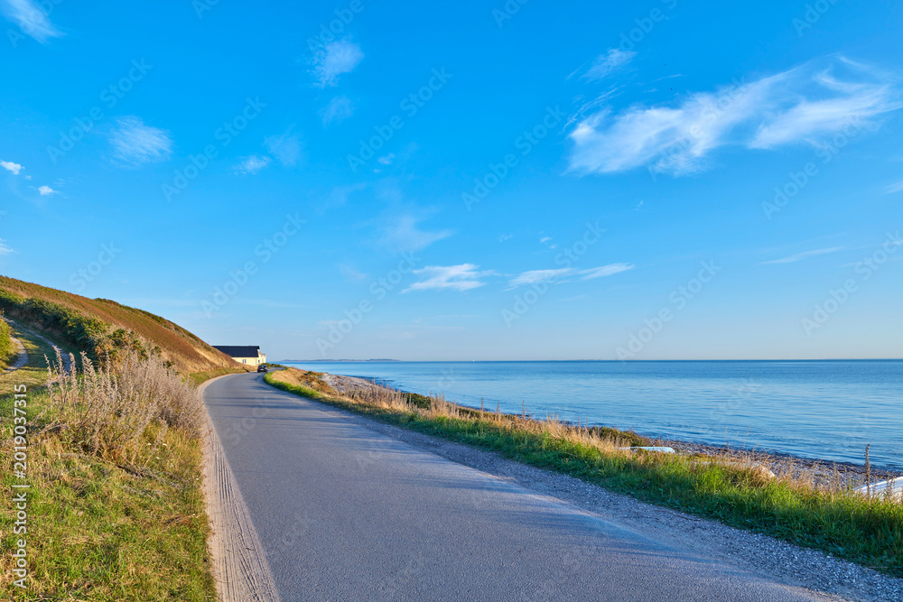Naklejka premium Coast, horizon and road in nature for commute or travel to remote destination in summer season. Asphalt street, ocean and wallpaper with direction, path or route outdoor for landscape or scenic view