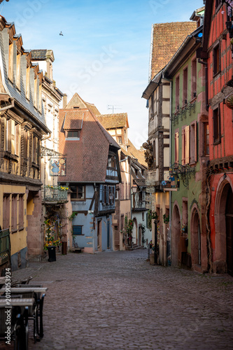 Φωτογραφία Sunlit medieval street showing rustic half-timbered architecture and flower deco