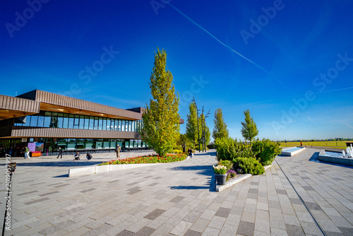LISSE, NETHERLANDS - APRIL 30, 2026: Modern building, tall trees and landscaped walkways at Keukenhof Gardens under a clear blue spring sky.