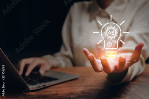 Innovation strategy, businesswoman holding glowing lightbulb with gear icons beside laptop, creative thinking and digital transformation