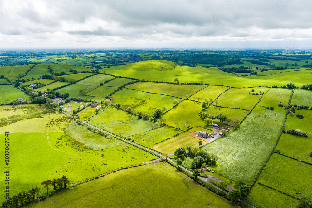 Fototapeta premium Patchwork fields spread across County Meath, Ireland, under heavy cloud. A peaceful Boyne Valley farming landscape of hedgerows, pasture and rural roads.