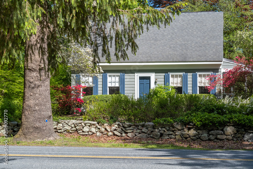 Charming cottage house with spring flowers and stone wall.