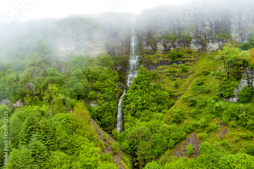 Devils Chimney Waterfall dropping through misty cliffs near Glencar Lough, Ireland. Dramatic cascade in the lush northwest landscape of County Sligo and Leitrim.