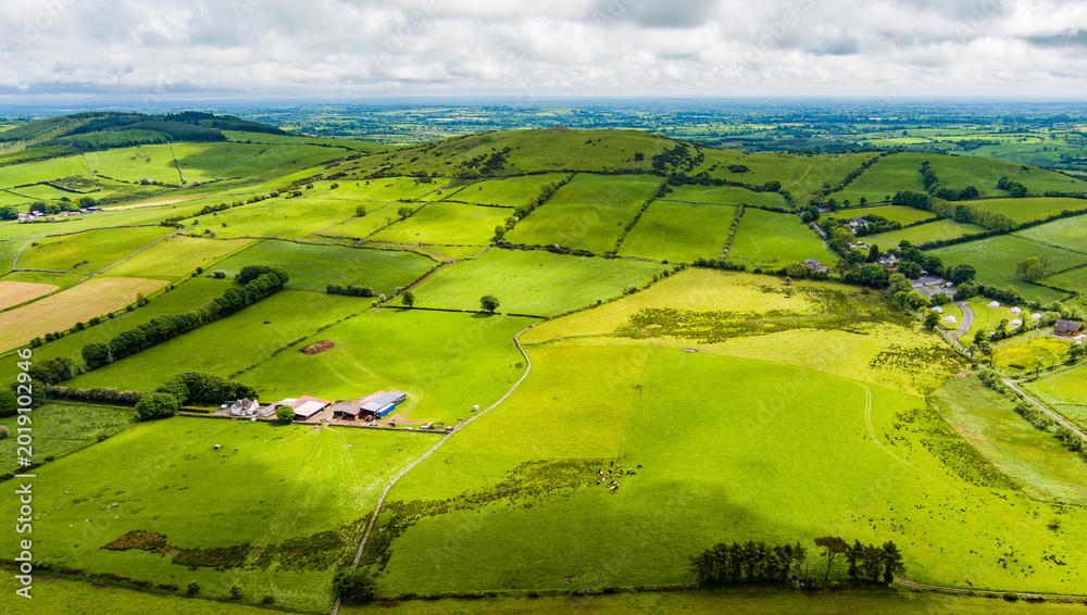 Fototapeta premium Patchwork fields spread across County Meath, Ireland, under heavy cloud. A peaceful Boyne Valley farming landscape of hedgerows, pasture and rural roads.