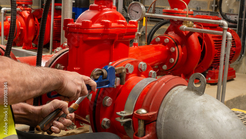 Canvastavla Sprinkler engineer tightening a pipe flange with spanners on a fire protection system during planned maintenance work