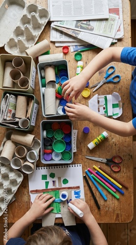 Children create art from recycled materials like bottle caps and cardboard. This Montessori activity promotes environmental awareness. Perfect for educational blogs or school projects.