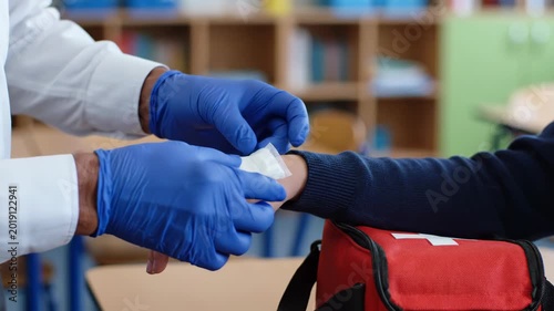 Medical professional applying bandage to injured arm in healthcare setting.