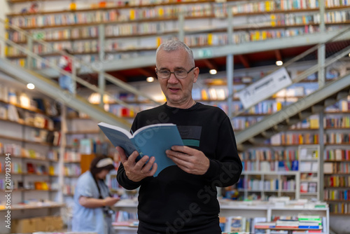 Canvastavla Man reading book in busy multi-level bookstore