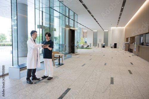 Bilde på lerret タブレットを見ながら指導や申し送りする医師と新人ドクターや看護師チーム連携イメージ全身