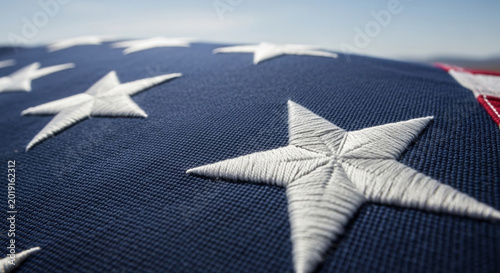 Close-up view of the embroidered white stars on the blue field of an American flag, symbolizing patriotism and national pride.