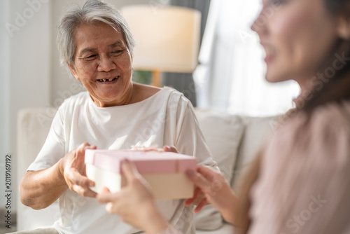 Fotografie Happy young adult asian daughter giving pink surprise gift box to senior mother