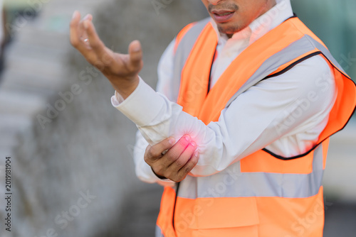 A male engineer suffered elbow pain from a work-related accident and injury. A male worker wearing protective work gear was also injured.