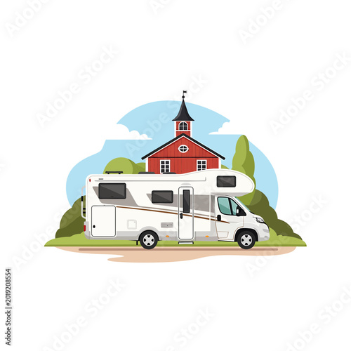 Modern motorhome parked in a scenic rural landscape with red building